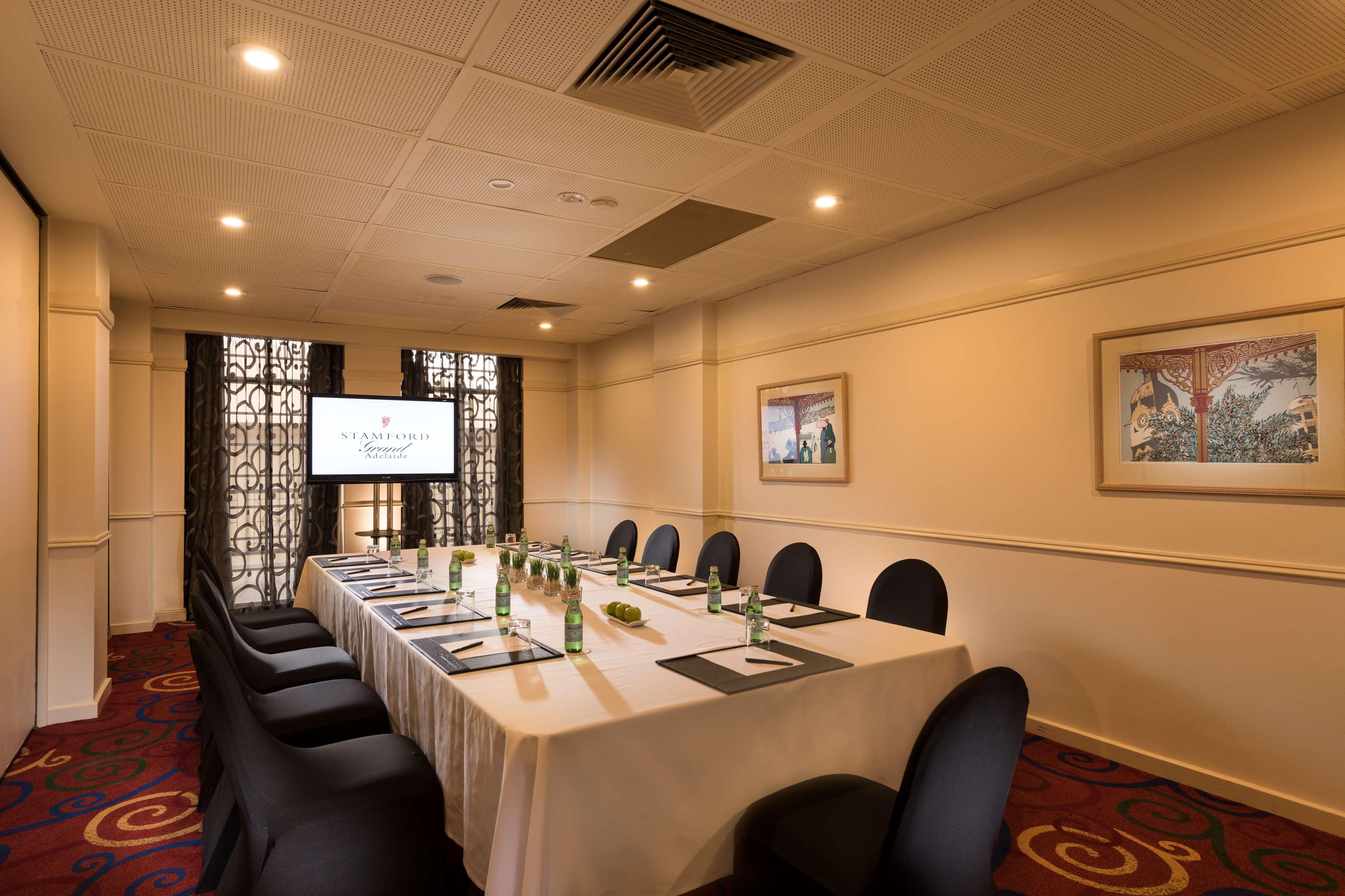 Hotel Stamford Grand Adelaide Glenelg Esterno foto The photo shows a conference room with a long rectangular table set for a meeting. The table is covered with a white tablecloth and has several place settings, including notebooks, pens, and water bottles. There are black chairs around the table, and