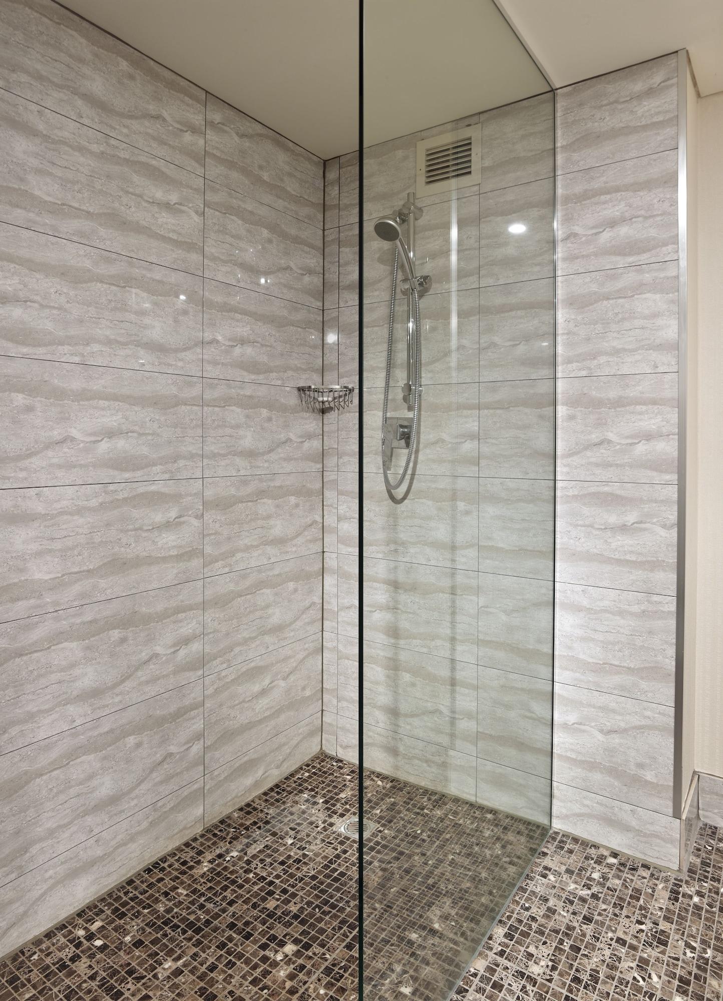 Hotel Stamford Grand Adelaide Glenelg Esterno foto The photo shows a modern shower enclosure with a transparent glass door. The interior features tiled walls in a light, marble-like pattern, creating a clean and sleek look. There is a showerhead mounted on the wall, and the floor appears to be tiled 
