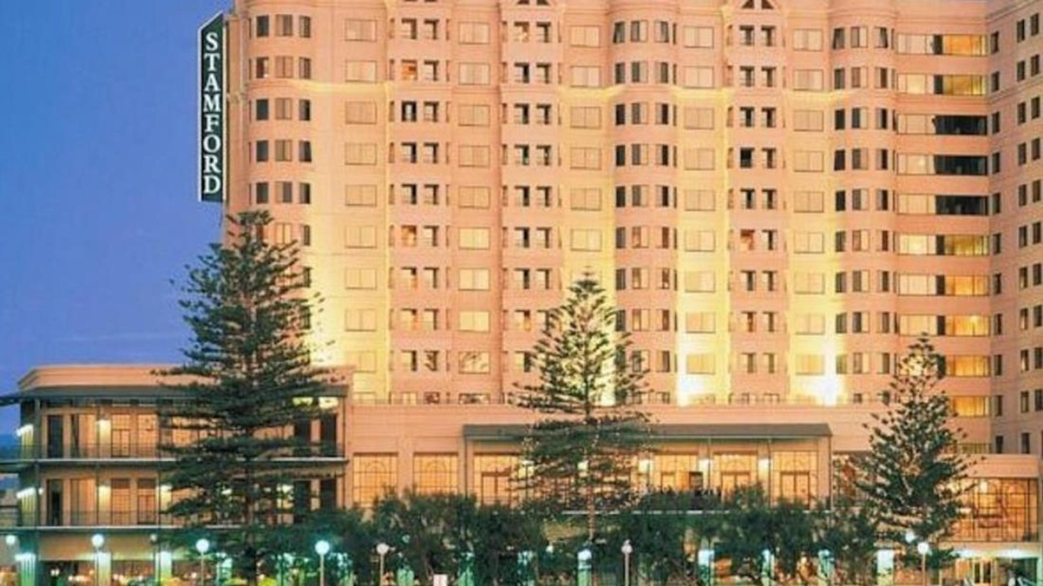 Hotel Stamford Grand Adelaide Glenelg Esterno foto The photo shows a tall, modern building illuminated at night, likely a hotel, with the name "Stamford" prominently displayed on its side. Surrounding the building are several palm trees and landscaped areas, suggesting a tropical or coastal location.