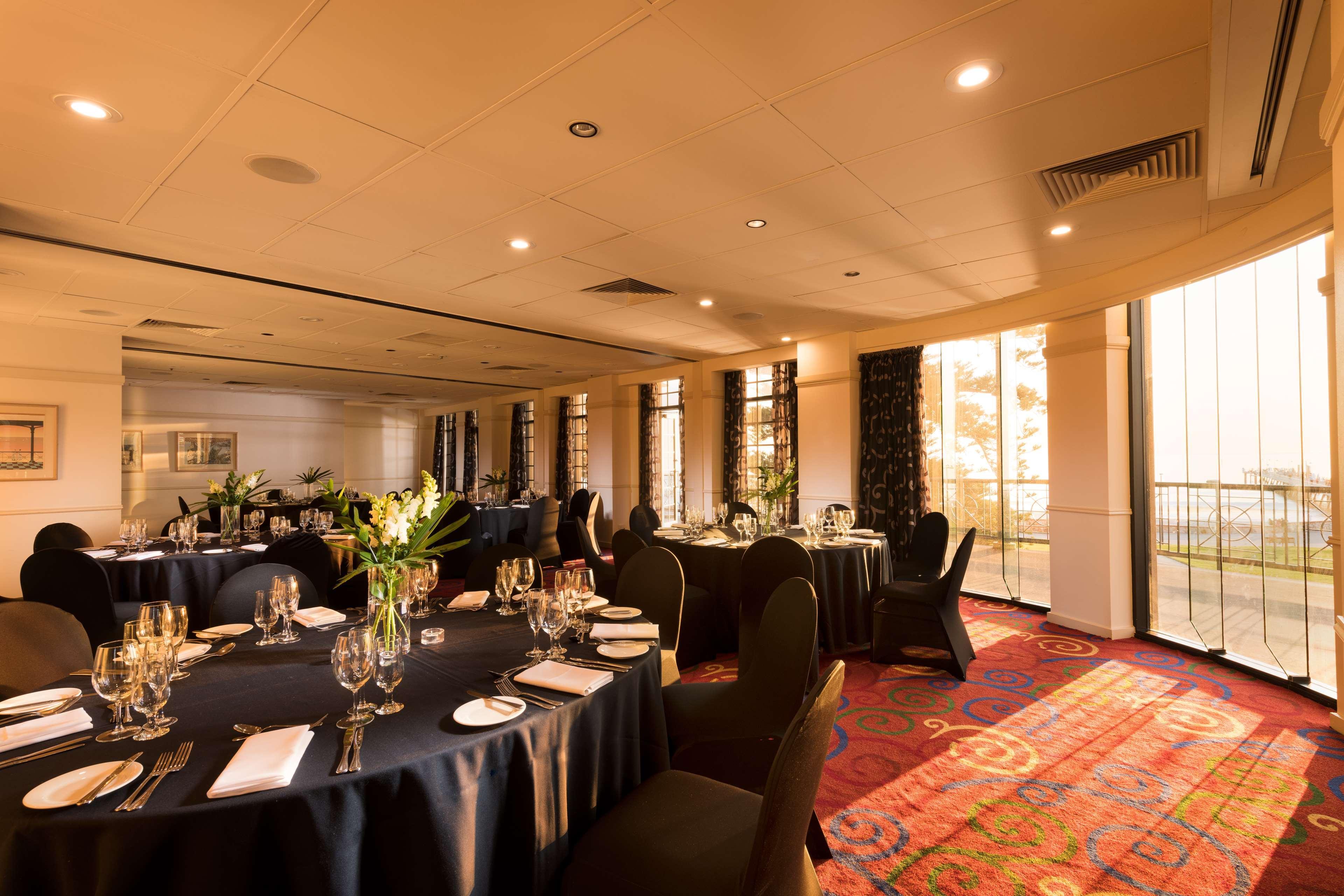 Hotel Stamford Grand Adelaide Glenelg Esterno foto The photo shows a well-decorated event space or dining area. There are several round tables draped in dark tablecloths, each set with elegant dinnerware, including glasses and cutlery. The room features large windows that allow natural light to flood