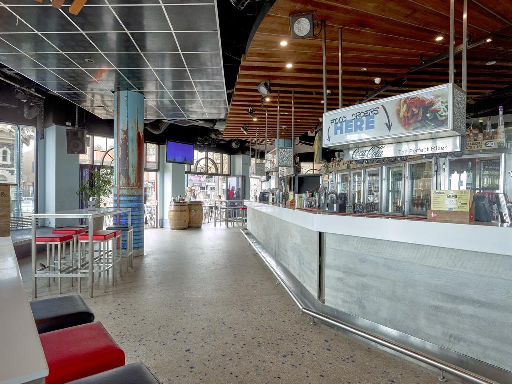 Hotel Stamford Grand Adelaide Glenelg Esterno foto The photo shows the interior of a modern bar or restaurant. The design features a long, white counter that serves as the bar area, with a glass display showing beverages. Behind the bar, there are shelves for drink storage. The space has a mix of sea