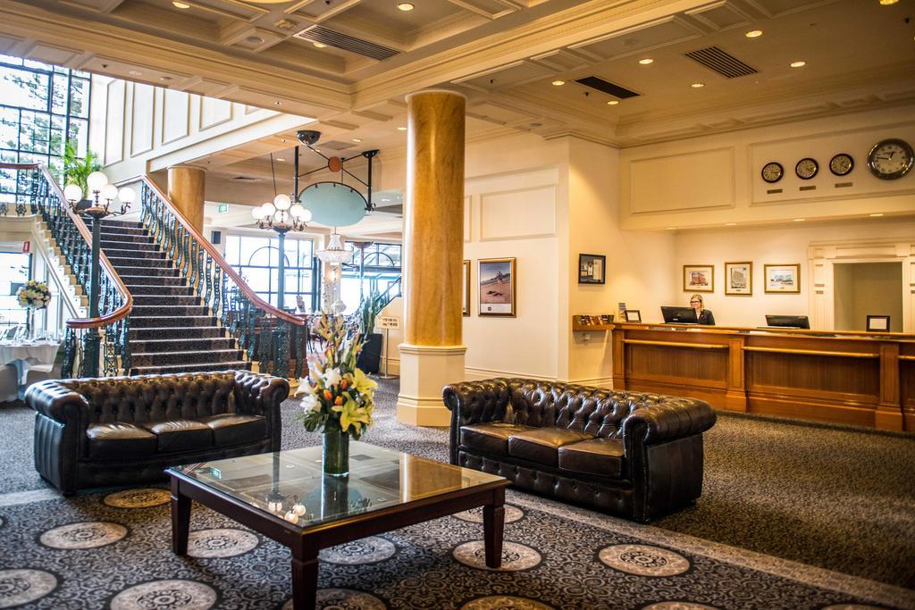 Hotel Stamford Grand Adelaide Glenelg Esterno foto The photo depicts a hotel lobby featuring a spacious and elegant design. There are two dark leather sofas arranged in front of a glass coffee table, adorned with a floral centerpiece. The lobby has a refined atmosphere, highlighted by large windows t