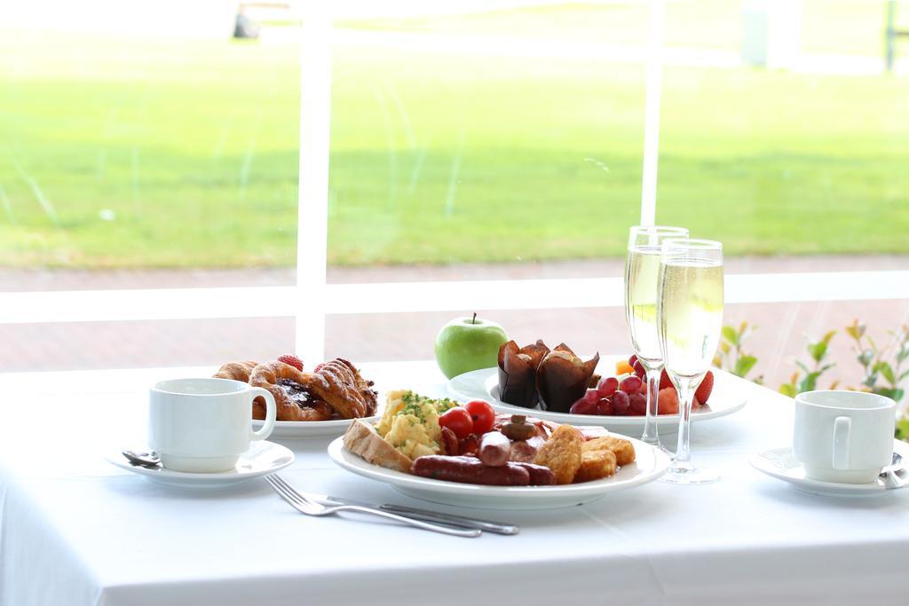 Hotel Stamford Grand Adelaide Glenelg Esterno foto The photo displays a beautifully arranged breakfast setup on a white tablecloth. In the center, there is a large white plate with a variety of foods, including eggs, sausage, and fresh fruit. Surrounding the plate are a few other food items, such as 